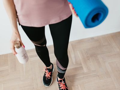 Close-up of a yoga mat and water bottle on a wooden floor.